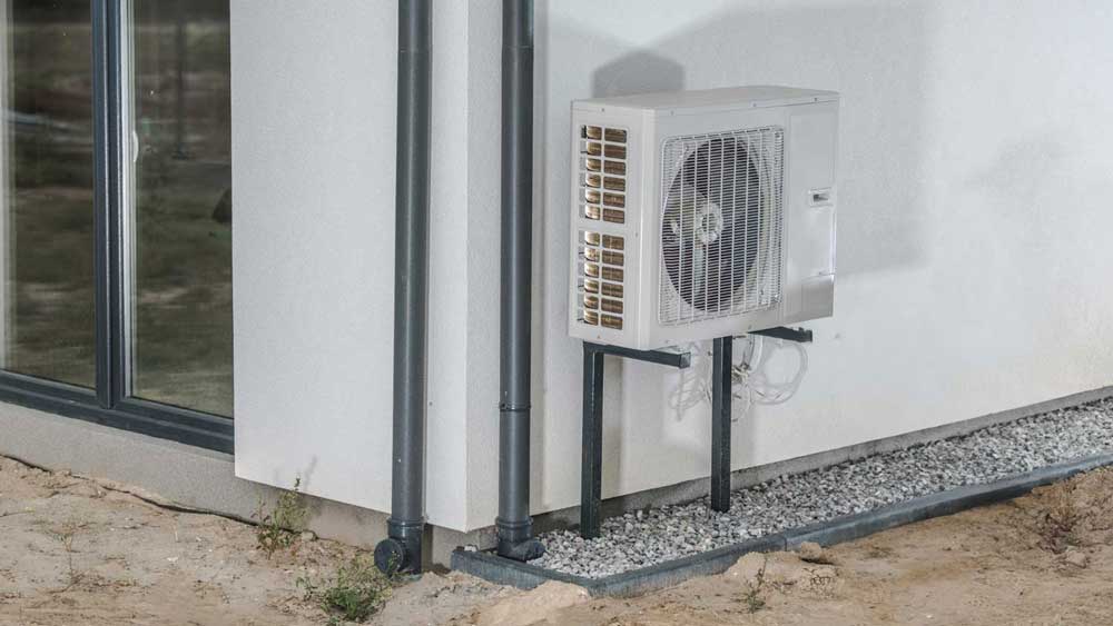 Outdoor mini-split AC unit mounted on a wall with metal brackets