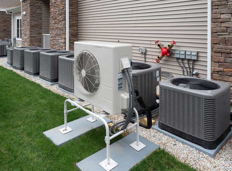 Air conditioning units lined up outside a building on a gravel bed