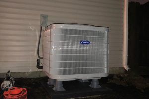 Carrier air conditioning unit installed outside a house at night
